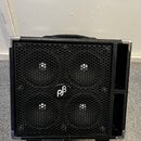 Černý basový reproduktor v kostce s povrchem z texturovaného vinylu a kovovými rohy. Přední stranu tvoří černá kovová mřížka s logem "pβ" v kruhu upr…
