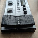 Stříbrný efektový pedál s černými ovládacími prvky a expresním pedálem. Na horní části je nápis BOSS GT-1B BASS EFFECTS PROCESSOR a na expresním pedá…