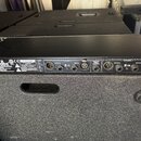 Černý rackový procesor značky dbx. Na předním panelu jsou nápisy „CHANNEL 2“ a „CHANNEL 1“, sekce „OUTPUTS“ a „INPUTS“ s konektory XLR a jack. V levé…