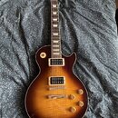 Elektrická kytara s trupem v barvě sunburst a viditelnou strukturou dřeva. Na hlavě hmatníku je bílé logo Ibanez. Nástroj má dva humbuckery, čtyři ov…