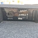 Zadní strana černého zesilovače s látkovým potahem. Je zde vidět napájecí konektor s nápisy POWER a AC 240V-50Hz FUSE T2A/250V. Na přístroji je bílé…