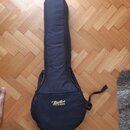Černý polstrovaný obal na hudební nástroj v tvaru kytary. Na spodní části je žlutý nápis „Boston“ a pod ním menší text „BAGS & STRAPS“. Obal je vyrob…