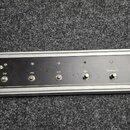 Šedý rackový spínací panel s hliníkovým rámem. Na levé straně je logo Dual Rectifier a pod ním nápis ROADSTER, vpravo dole je logo MESA Engineering.…
