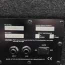 Fotografie zachycuje zadní panel černého reproduktoru s dvěma konektory a jedním přepínacím tlačítkem. Na panelu jsou nápisy Model No: LC41063, Seria…