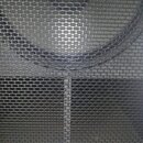 Detailní pohled na černou kovovou ochrannou mřížku reproduktoru s oválnými otvory. V dolní části je nalepený modrý obdélníkový štítek s bílým nápisem…