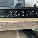 Zadní strana černého elektronického zařízení s řadou konektorů. Jsou zde nápisy POWER, 12V DC, HDMI, CLICK, AUX MON., PHONES, MAIN, LINE IN, MIC 2 a…