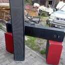 Sada černých a červených reproduktorových beden různých tvarů. Jedna bedna je vysoká, úzká a černá s přední textilní mřížkou, druhá je dlouhá, vodoro…