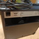 Zadní strana černého kytarového komba s texturovaným povrchem. Na horním štítku jsou nápisy POWER REQUIREMENTS, 220-240V ~, 50 - 60Hz, 75 W Max. a vp…