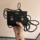 Černý efektový pedál značky Marshall s dvěma stoupacími spínači. Nad levou spínacíю je nápis BOOST a červená kontrolka, nad pravou nápis FX LOOP. V p…