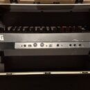 Černý syntetizátor KORG modwave WAVETABLE SYNTHESIZER umístěný v otevřeném transportním kufru. Na zadní straně přístroje jsou vidět konektory a nápis…