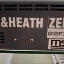 Detailní pohled na šedý kovový panel s ventilačními otvory. Na panelu je bílý nápis EN&HEATH a vedle něj štítek s označením ZED 22FX. V pravém dolním…