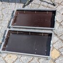 Otevřený hliníkový kufřík s černým vnitřním povrchem. Kufřík má kovové hrany a rohové zpevnění. Na vnitřních stěnách jsou vidět šrouby pro upevnění v…