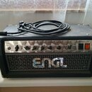 Černý kytarový kombozesilovač s nápisem ENGL na předním mřížkovém krytu. Na horním ovládacím panelu jsou nápisy Input, Gain, Bass, Middle, Treble, Cr…