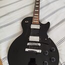 Černá elektrická kytara s tmelem hmatníkem a dvěma humbuckery v chromovém provedení. Na těle je umístěn černý pickguard a čtyři ovládací knoflíky. V…