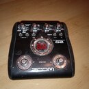 Černý kytarový efekt pedál s nápisem ZOOM a označením GUITAR EFFECTS PEDAL G2. Horní část obsahuje několik otočných potenciometrů a tlačítek, včetně…