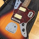 Elektrická kytara s trupem v barevném přechodu od černé přes červenou k žluté a hnědým hmatníkem. Nástroj má červeně vzorovaný pickguard, tři snímače…