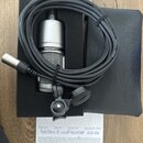 Stříbrný kondenzátorový mikrofon s mřížkou, na kterém je nápis audio-technica. Součástí je černý kabel s XLR konektory, černý držák a černý ochranný…