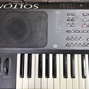 Černý elektronický klavír s nápisem SOLTON by KETRON lab. Na ovládacím panelu je seznam DRUM SET od 1 do 13 a různé ovládací tlačítka, včetně loga GE…