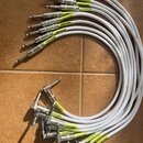 Sada bílých instrumentálních kabelů s konektory typu jack. Na žlutých štítcích u konektorů je nápis INSTRUMENT nebo nečitelný text. Kabely mají kovov…