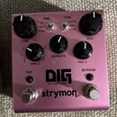 Růžový efekt pedál s nápisy DIG dual digital delay a strymon. Na horní straně jsou čtyři černé otočné ovladače s popisky TIME, REPEATS a MIX, přičemž…