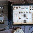 Na fotografii je černý reproduktor značky K.C.S. s nápisem SR-8/2 Professional Music Monitor a bílý mixážní pult v černém přepravním kufru. Mixážní p…
