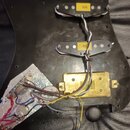 Černý plastový pickguard s instalovanými dvěma snímači s bílými plastovými krytkami. Na snímačích jsou žluté štítky s nápisy RS1 a RS2. V dolní části…