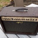 Hnědý akustický kombozesilovač s texturovaným povrchem a černou přední síťovkou. Na horním ovládacím panelu je nápis ACOUSTIC AMPLIFIER a logo MEGA A…