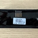 Černý elektrický snímač s plastovým krytem. Na spodní straně je bílá nálepka s nápisy EMG-HZ7A, (21)1585932 CE a 10/31/08 MADE IN USA. Mezi nálepkou…