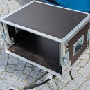 Černý transportní case s hliníkovými hranami a rohy. Box je otevřený, vnitřní prostor je prázdný a černý. Na boční straně je umístena integrovaná pla…