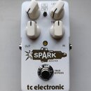 Bílý kytarový efekt s čtyřmi bílými oválnými knoflíky. Na pedálu jsou nápisy FAT CLEAN MID, LEVEL, TREBLE a logo SPARK BOOSTER s motivem zapálené záp…
