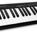 Černý MIDI kontrolér s klávesnicí. Na horním panelu je bílý nápis ALESIS Q49 USB/MIDI KEYBOARD CONTROLLER. Nástroj má v levé části dva ovládací posuv…