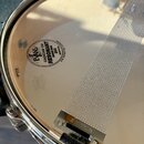 Fotografie zachycuje spodní část snare bubnu s kovovým obručím. Na bláně je černý nápis EVANS CADICAM 190 RESONANT SNARE SIDE 300 MADE IN USA U.S. PA…