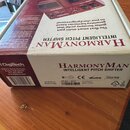 Kartonová krabice od efekt pedálu v červené a bílé barvě. Na krabici je nápis HARMONYMAN INTELLIGENT PITCH SHIFTER a logo DigiTech. V dolní části je…