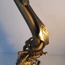 Detail saxofonu v matné zlaté barvě. Na zakřiveném hrdle je vyryto logo ve tvaru stylizovaného písmena S. Povrch nástroje je hladký a bez viditelných…