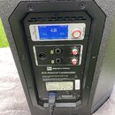 Zadávací panel černého aktivního reproduktoru s nápisy "Electro-Voice" a "ETX Powered Loudspeaker". Panel obsahuje modrý LCD displej s textem "-4dB",…