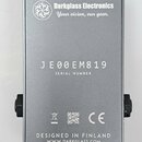 Zadní strana stříbrného efekt pedálu z kovu. V horní části je logo a nápis Darkglass Electronics Your vision, our gear. Uprostřed je uvedeno sériové…