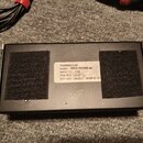 Černý obdélníkový napájecí zdroj s dvěma velkými úseky suchého zipu na spodní straně. Uprostřed je bílá nálepka s nápisy VOODOO LAB, MODEL: PEDAL POW…