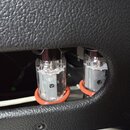 Detailní pohled na dvě elektronky v černém šasi s texturovaným povrchem. Elektronky jsou zasazeny do červených gumových prstenců; na jedné je čitelně…
