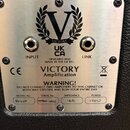 Kovová zadní deska kytarového cabinetu s dvěma vstupy označenými jako INPUT a LINK. Na desce je umístěno logo Victory s písmenem V v vavřinovém věnci…