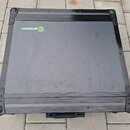 Černý transportní kufr s kovovými hranami a rohovými zpevněními. Na spodní části je viditelné zelenobílé logo s nápisem fu generation. Povrch kufrů v…