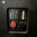 Fotografie zachycuje zadní panel černého reproduktoru. Na štítku je uveden nápis YAMAHA, SPEAKER SYSTEM, MODEL NS-10M STUDIO, NOMINAL IMPEDANCE 8 OHM…
