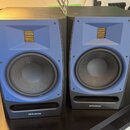 Dva studiové monitory v černých skříních s modrými předními panely. Na spodní části obou reproduktorů je bílý nápis PreSonus s logem. Povrchy jsou v…