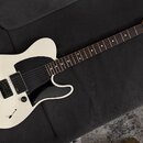 Bílá elektrická kytara s černým pickguardem a hnědým hmatníkem. Na hlavě je vidět nápis Squier by Fender a TELECASTER. Kytara má jeden snímač u kobyl…