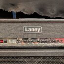 Černý kytarový kombozesilovač značky Laney. Na předním panelu je nápis GH100L a řada ovládacích prvků s popisky POWER, STANDBY, RESONANCE, PRESENCE,…