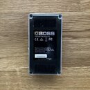 Zadní strana efektového pedálu v kovovém šasi stříbrné barvy. Na černém štítku je bílým písmem uveden nápis BOSS, CAN ICES-3 (B)/NMB-3 (B), loga CE,…
