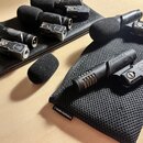 Fotografie zobrazuje několik černých mikrofonů s pěnovými kryty, umístěných na dvou černých pouzdrech. Na jednom z mikrofonů je čitelně nápis audio-t…