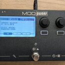 Černý kompaktní efektový procesor s nápisem MOD DWARF. Displej zobrazuje text DEVICE INFO, CURRENT RELEASE: v1.13.5.3315 a DEVICE SERIAL: MDWD02M02-0…