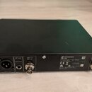 Zadní strana černého rackového přijímače. Na zařízení je nápis SENNHEISER, pod ním model EW-D EM a text Diversity Rack Receiver. Jsou zde viditelné k…