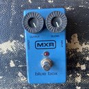 Modrý efekt pedál s dvěma černými oválnými ovladači. Na zařízení jsou nápisy OUTPUT, BLEND, MXR, INPUT a blue box. Povrch pedálu vykazuje známky opot…