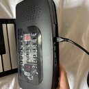 Černý plastový elektronický přístroj s ovládacím panelem a digitálním displejem. Na panelu jsou tlačítka s nápisy Tone, OOP, Dual K, Sustain, Vibrato…